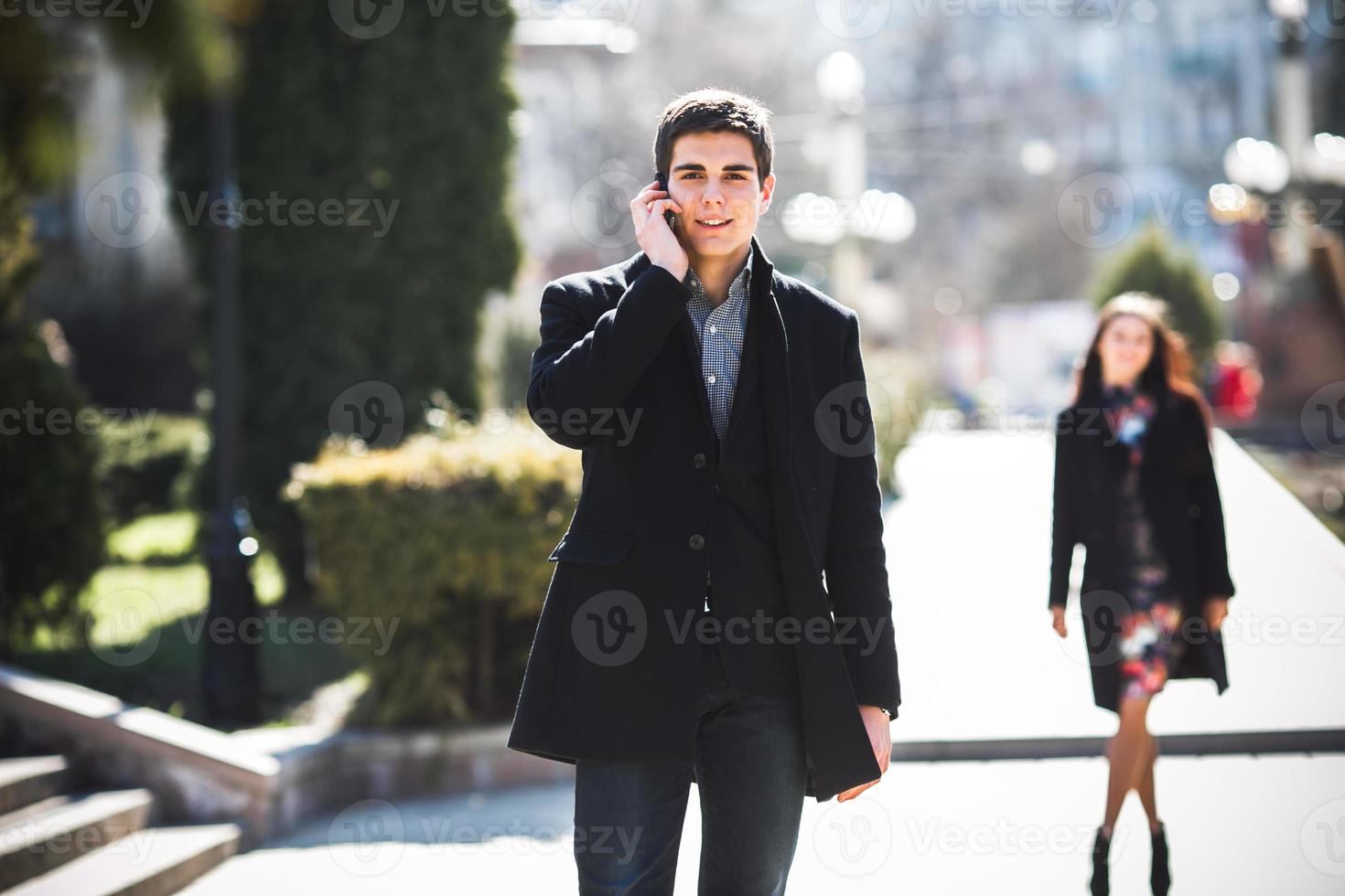 businessman talking on the phone while woman comes to him photo