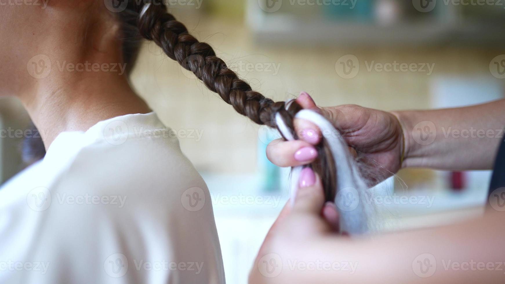 Process of braiding. Master weaves braids on head in a beauty salon, close up photo