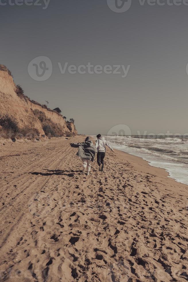 Man and woman enjoy each other, run along the seashore photo