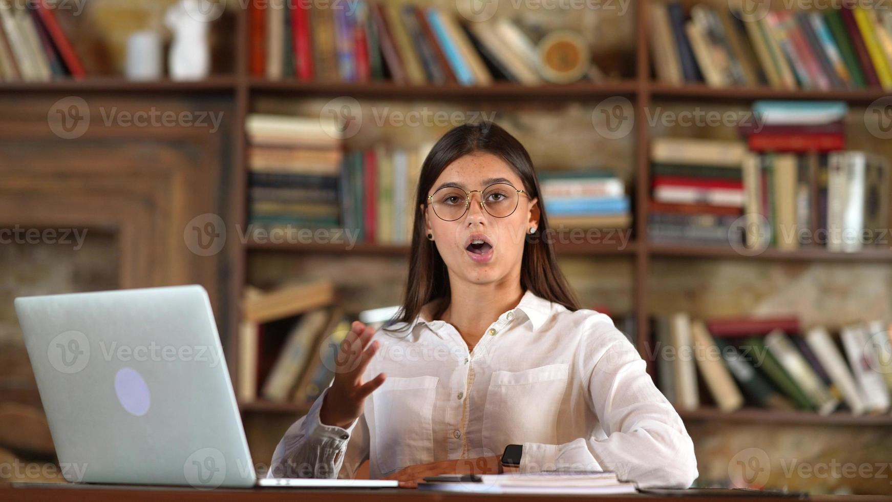 Business woman in glasses sits and talking to the camera photo