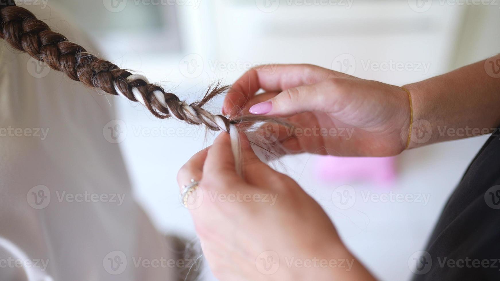 Process of braiding. Master weaves braids on head in a beauty salon, close up photo