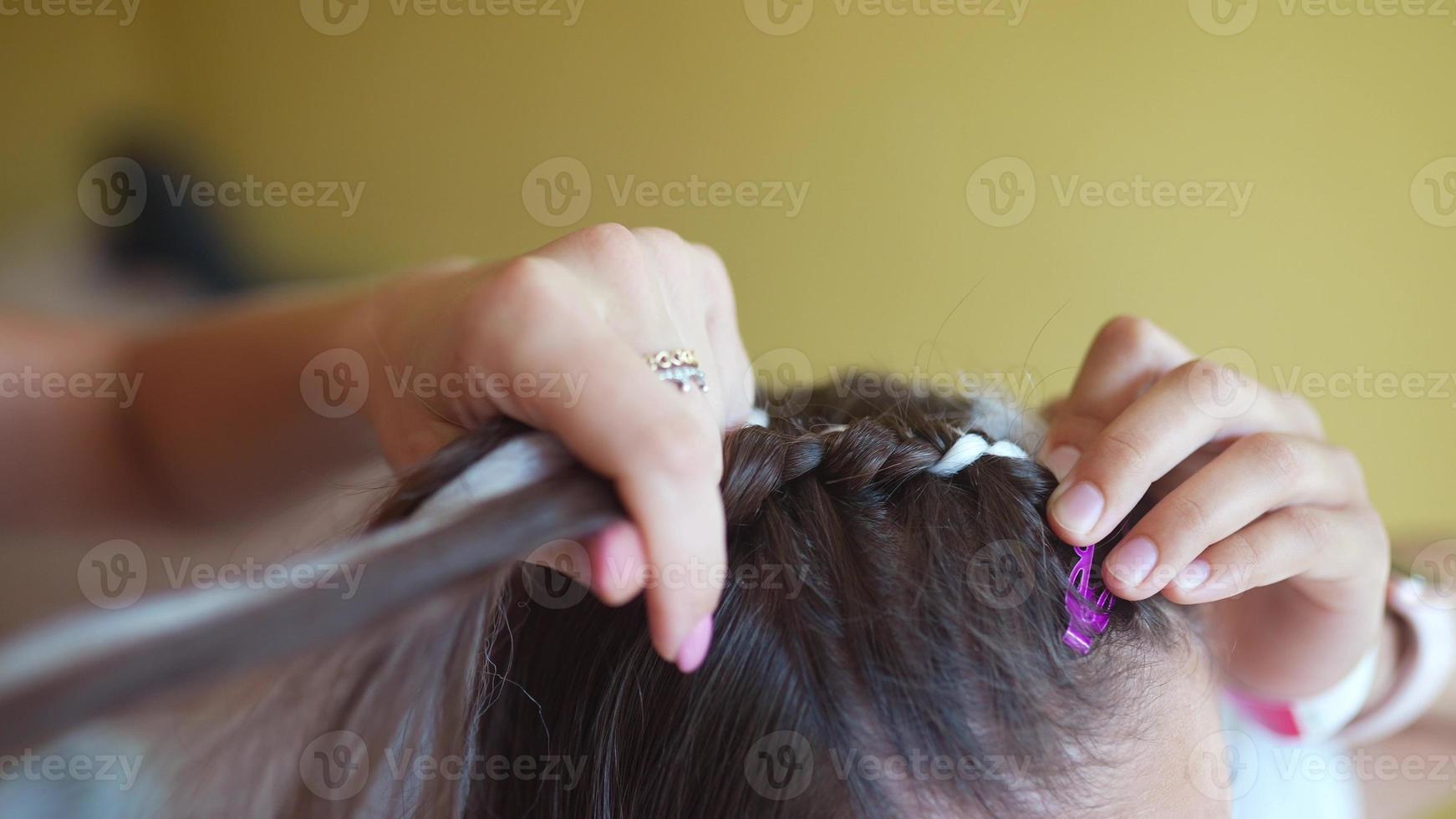 Process of braiding. Master weaves braids on head in a beauty salon, close up photo