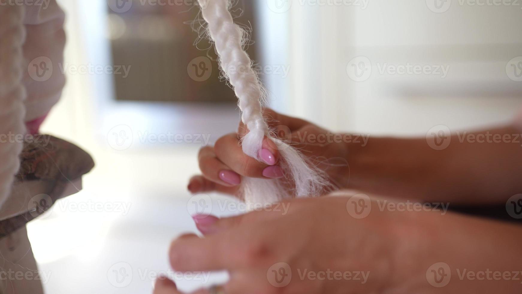 una peluquera teje una trenza de un kenekalon blanco. primer plano del proceso foto