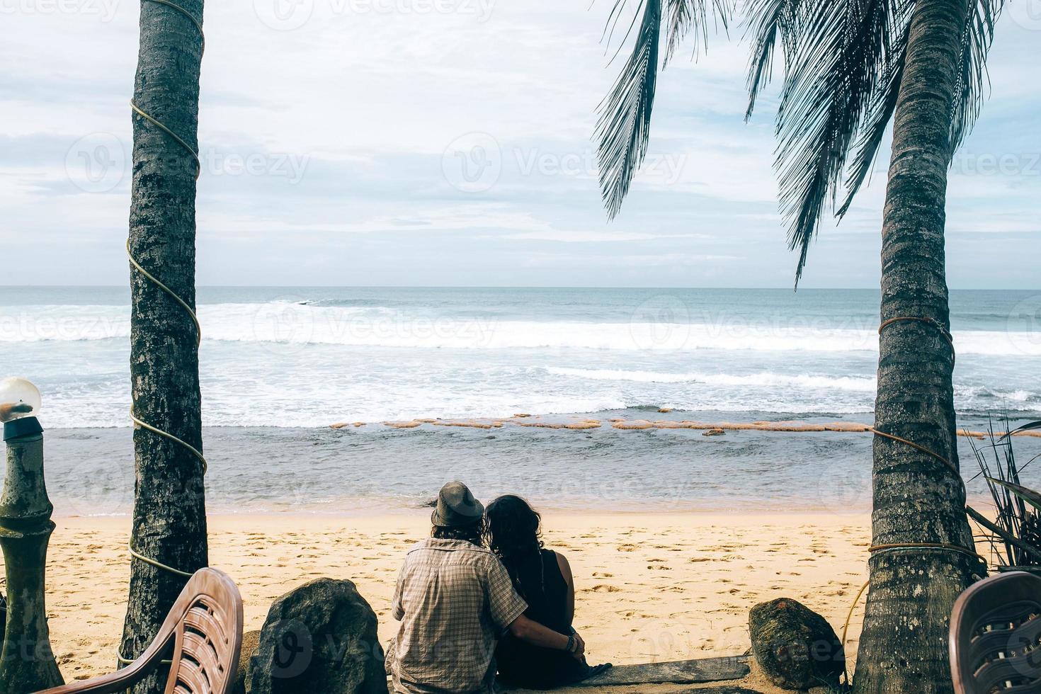 couple sitting under palm trees photo