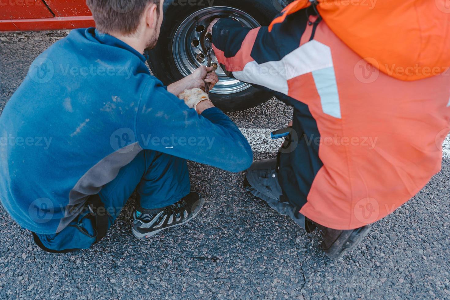 Man unscrews the bolts on the wheel photo