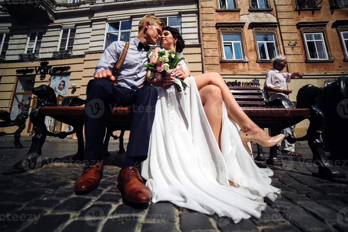 bride and groom sit on the bench photo