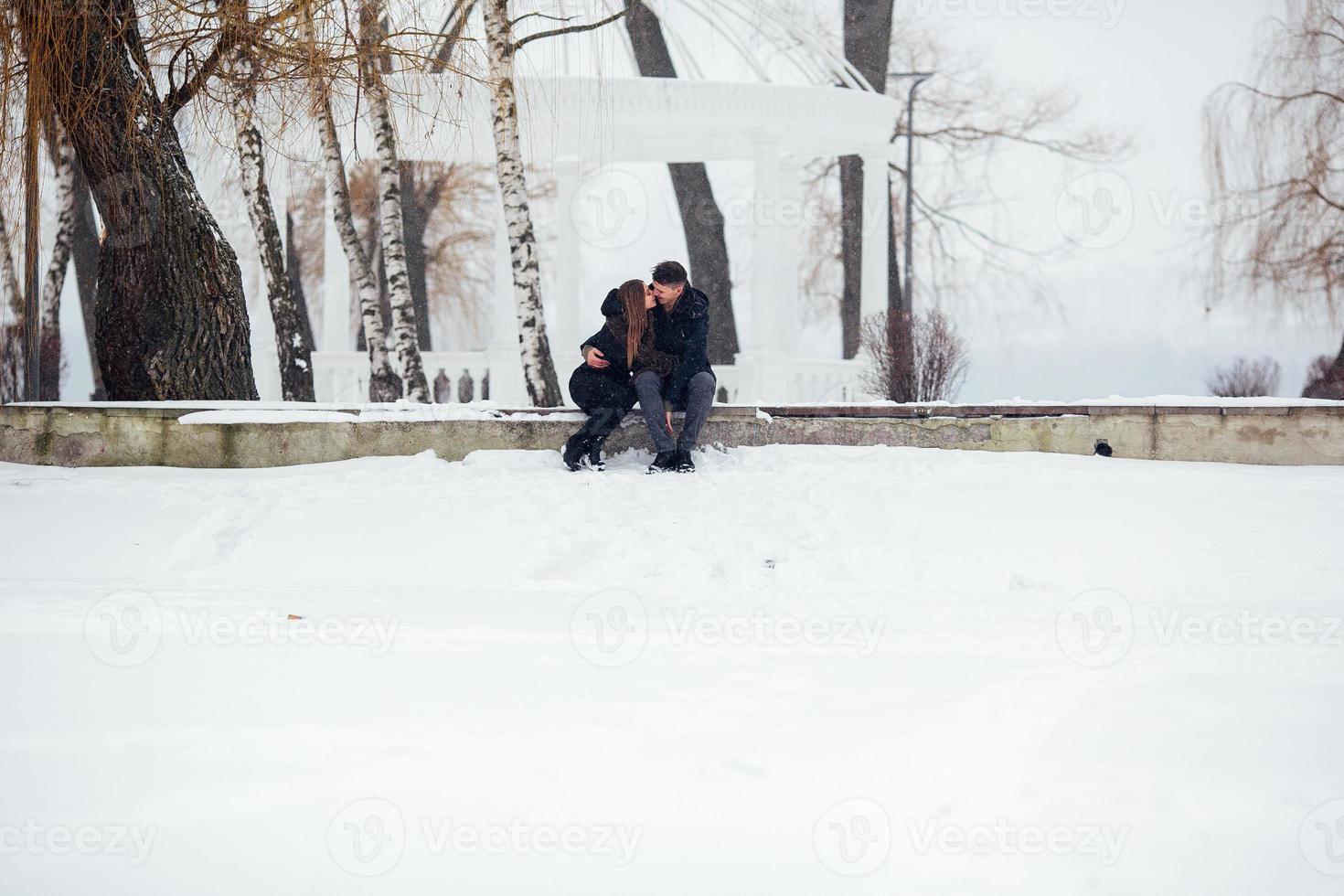 man and woman kissing in snowy park photo