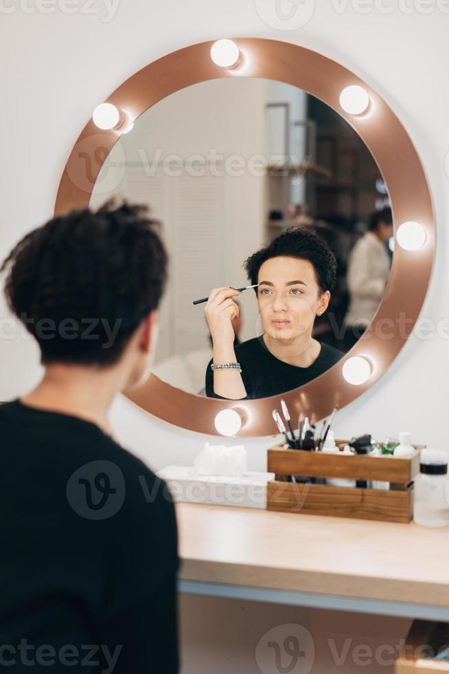Attractive woman at the mirror in beauty studio photo