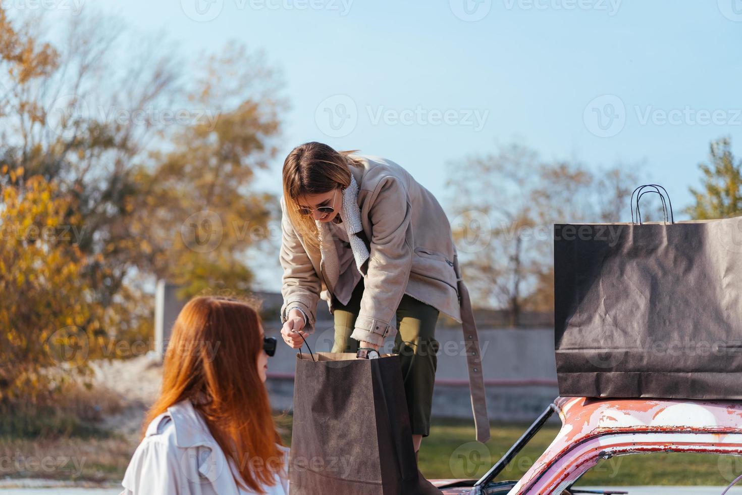 mujeres jóvenes posando cerca de un viejo auto decorado foto