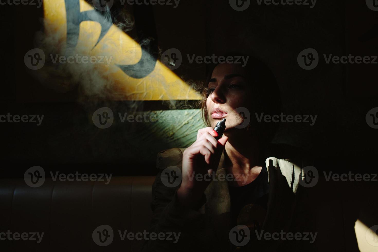 chica se sienta y fuma cigarrillo electrónico foto