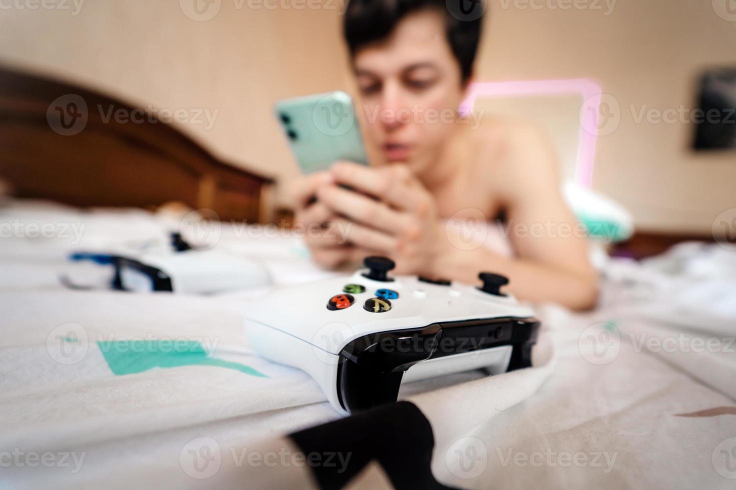 Close up shot of a guy lying in bed and using smartphone indoor. photo