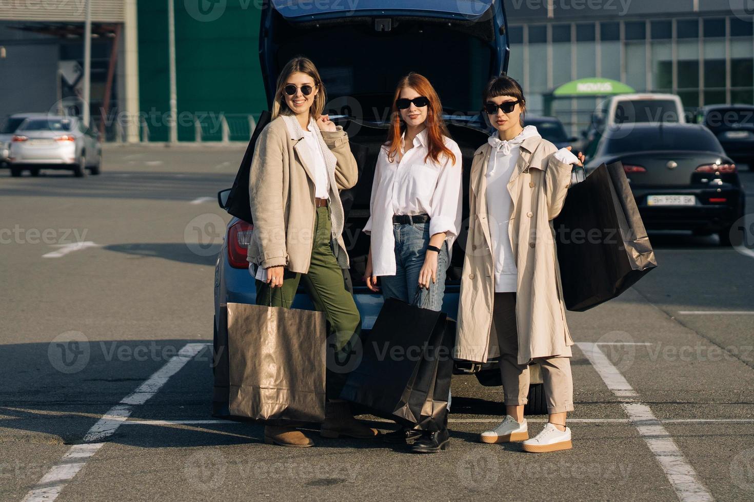 Young women at the car with shopping bags photo