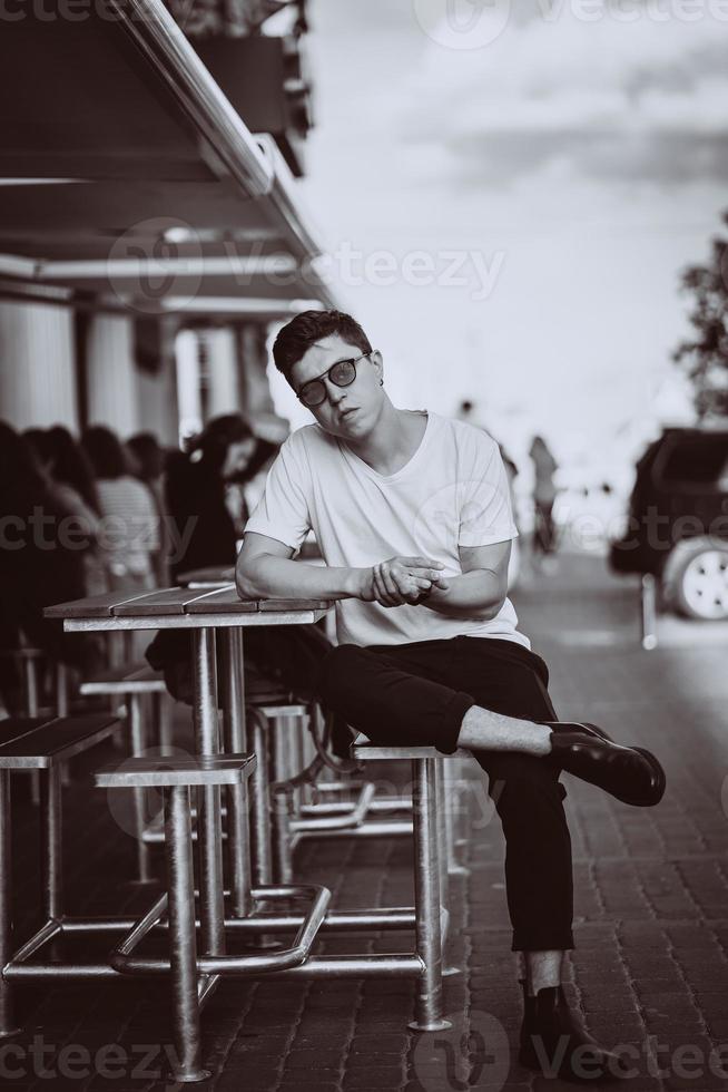 Guy sitting on the city street, look camera and around photo