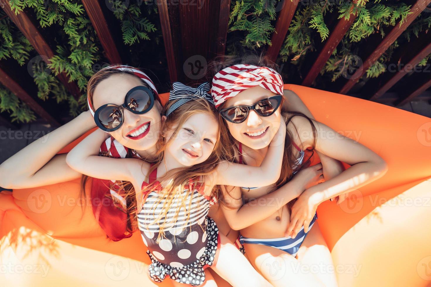 Beautiful mother with two daughters sitting on an orange lounge photo