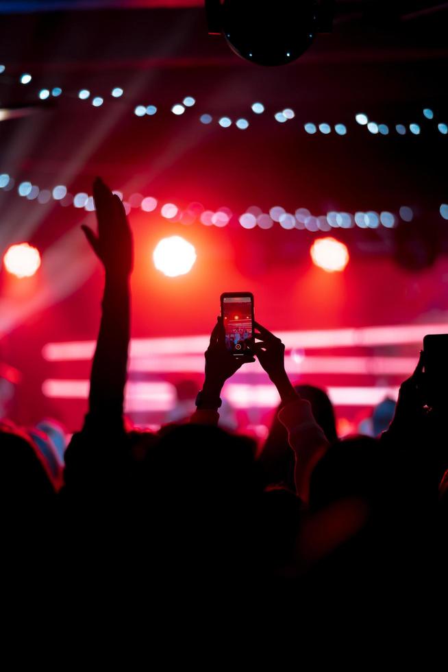 Person close up of recording video with smartphone during a concert. photo