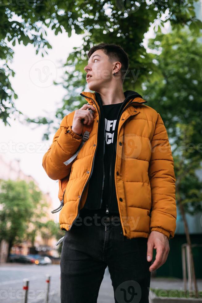 hombre adulto joven una chaqueta amarilla y jeans camina en una calle de la ciudad 11521917 Foto de stock en Vecteezy