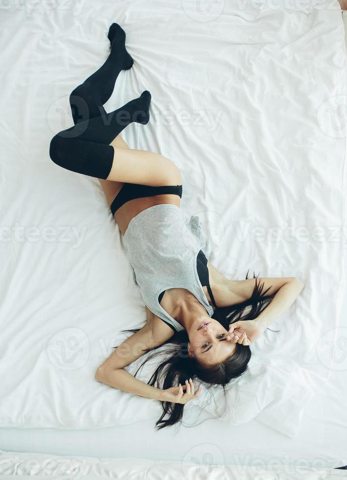 beautiful young girl posing on a white bed photo