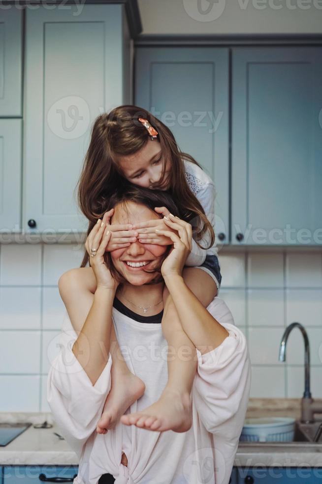 beautiful little daughter piggybacking on her happy mother photo