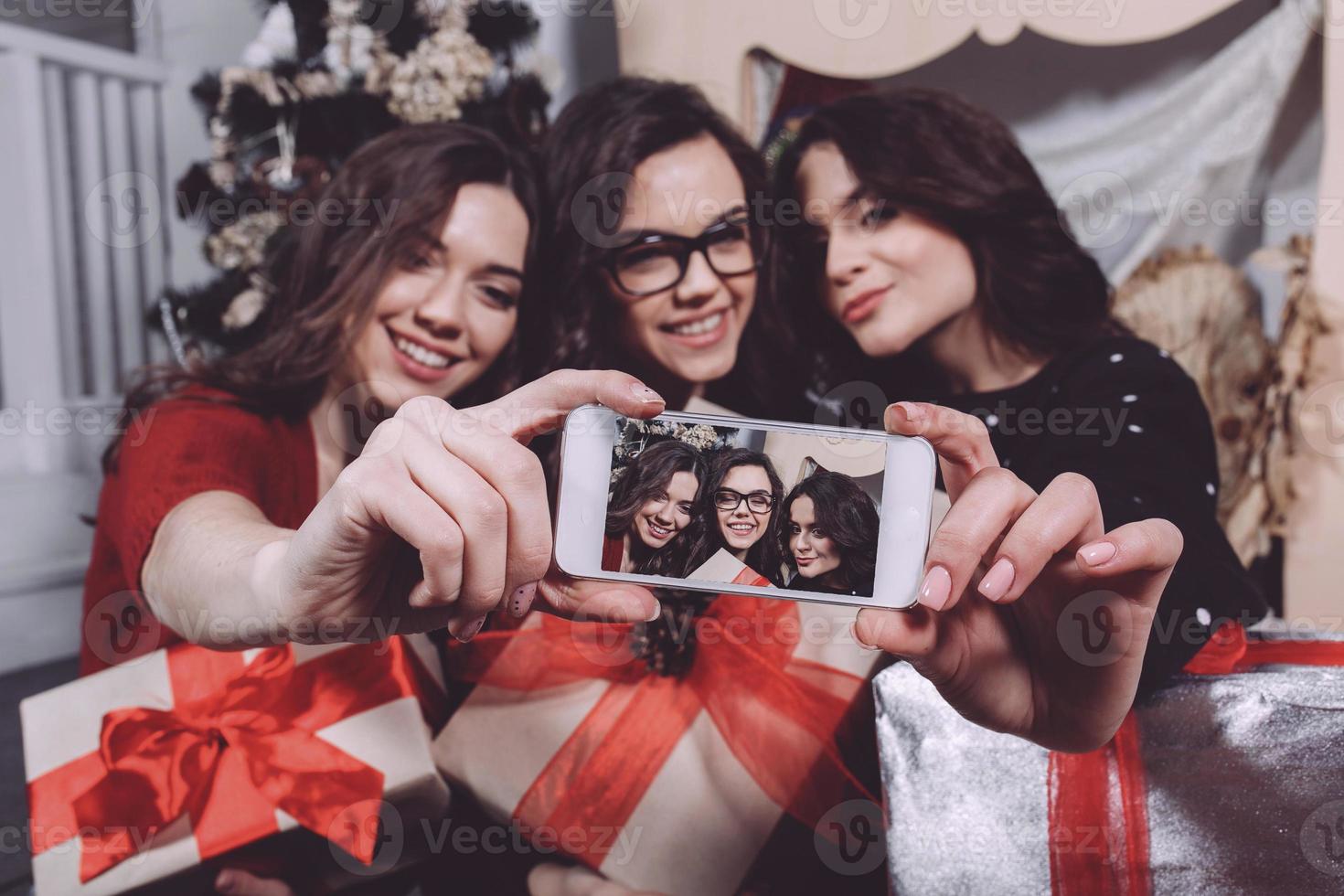 Beautiful girl photographed themselves on the phone on the background of Christmas gifts. Decorative vintage apartment. photo
