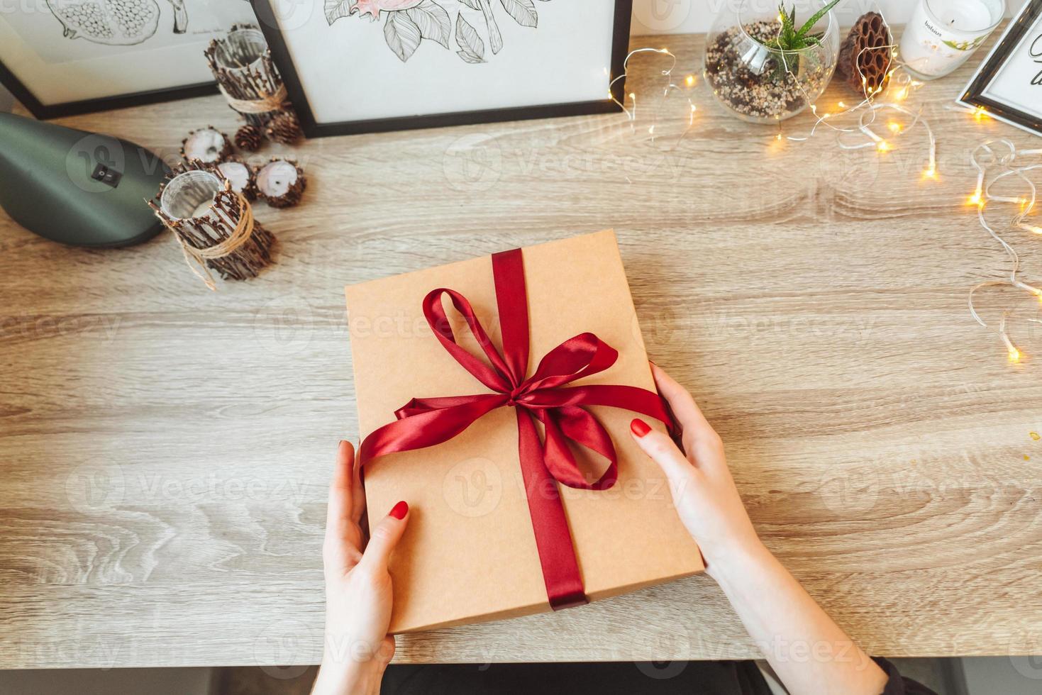 Woman wrapping present in paper with red ribbon. photo