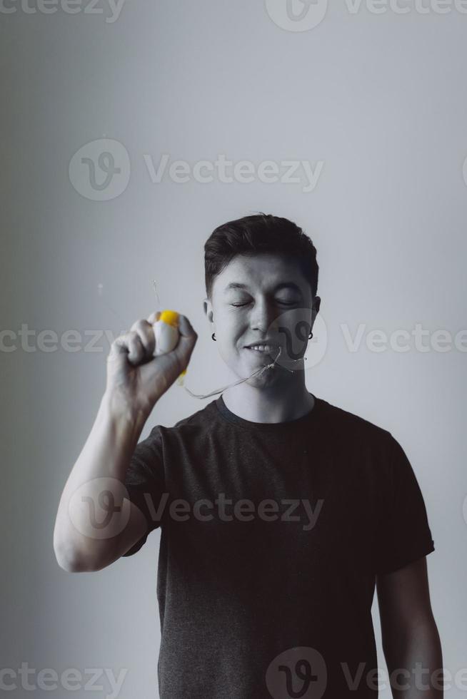 Guy crushes a chicken egg in his hand photo