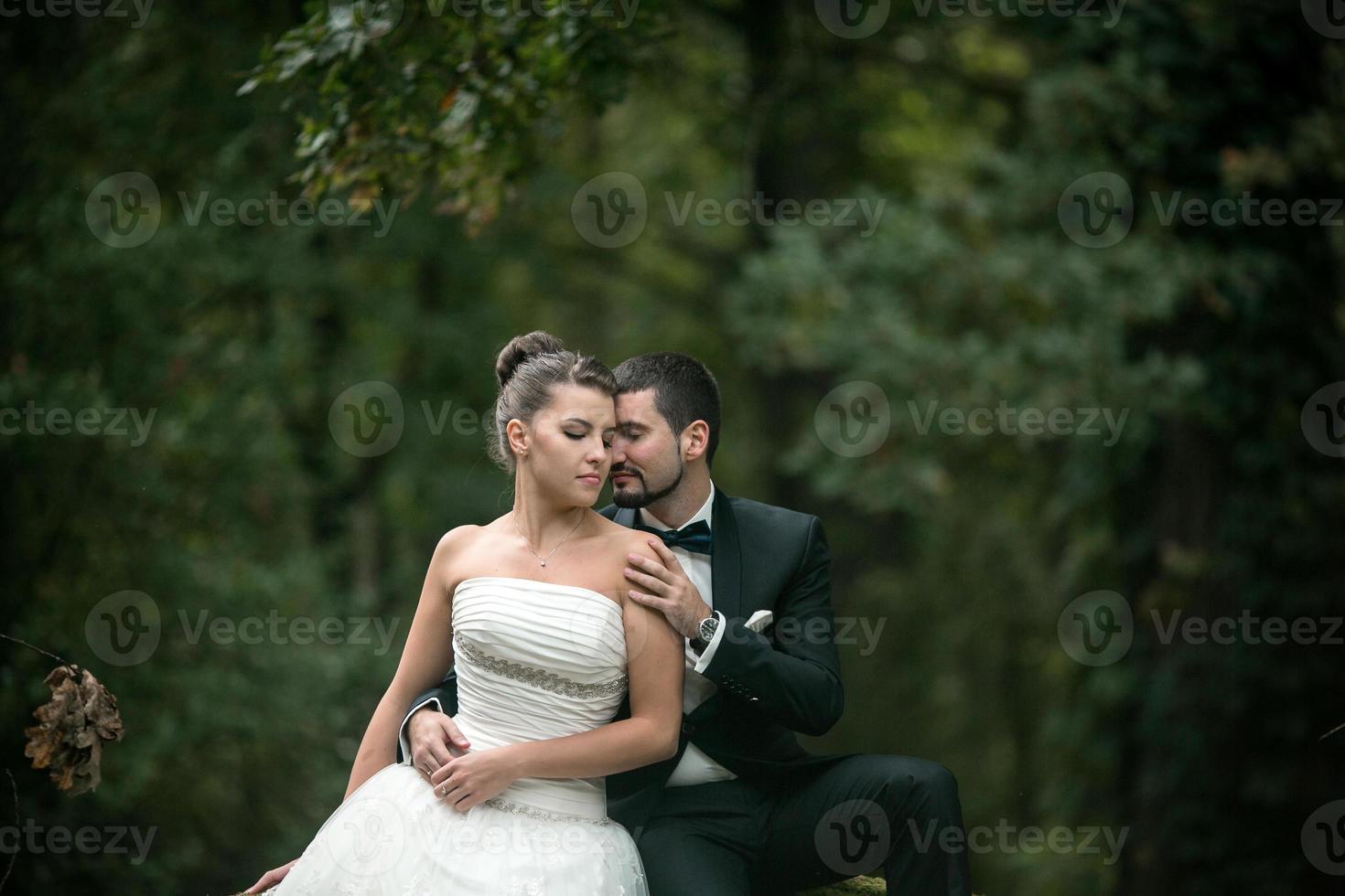 Beautiful wedding couple sitting in the woods photo