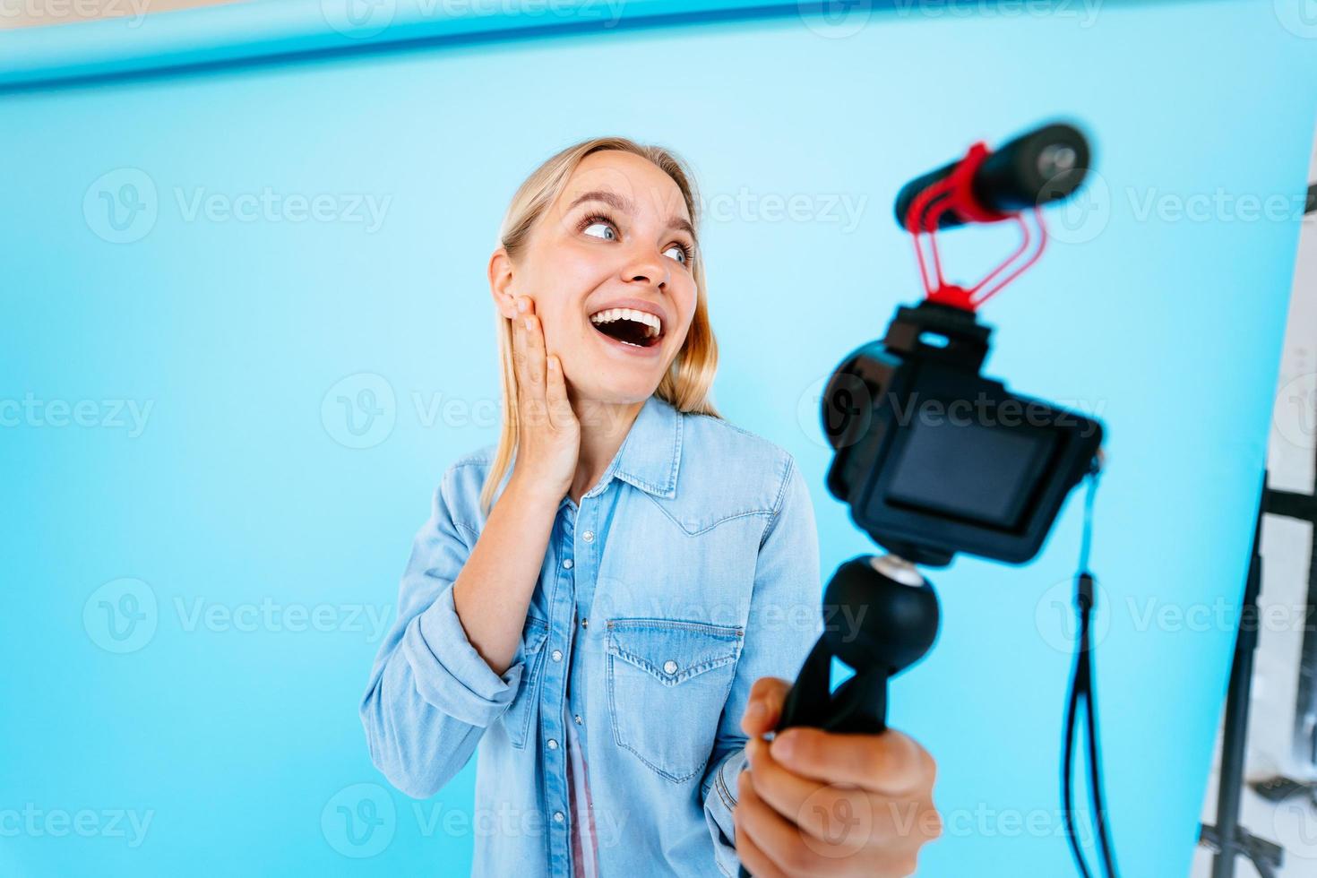 Beautiful girl blogger relieves itself at camera isolated blue background photo