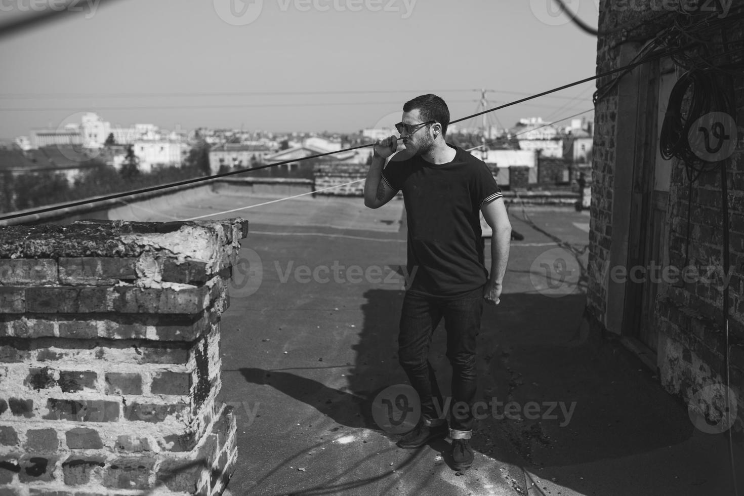 El hombre de las botas auténticas y el orillo de jeans en el techo del edificio en el casco antiguo foto