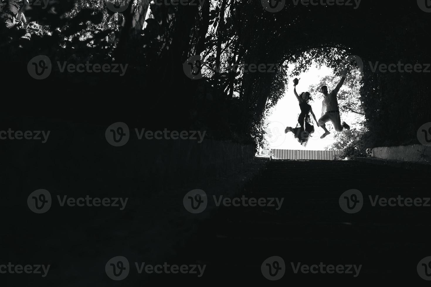 couple jumping in the end of tunnel with trees photo