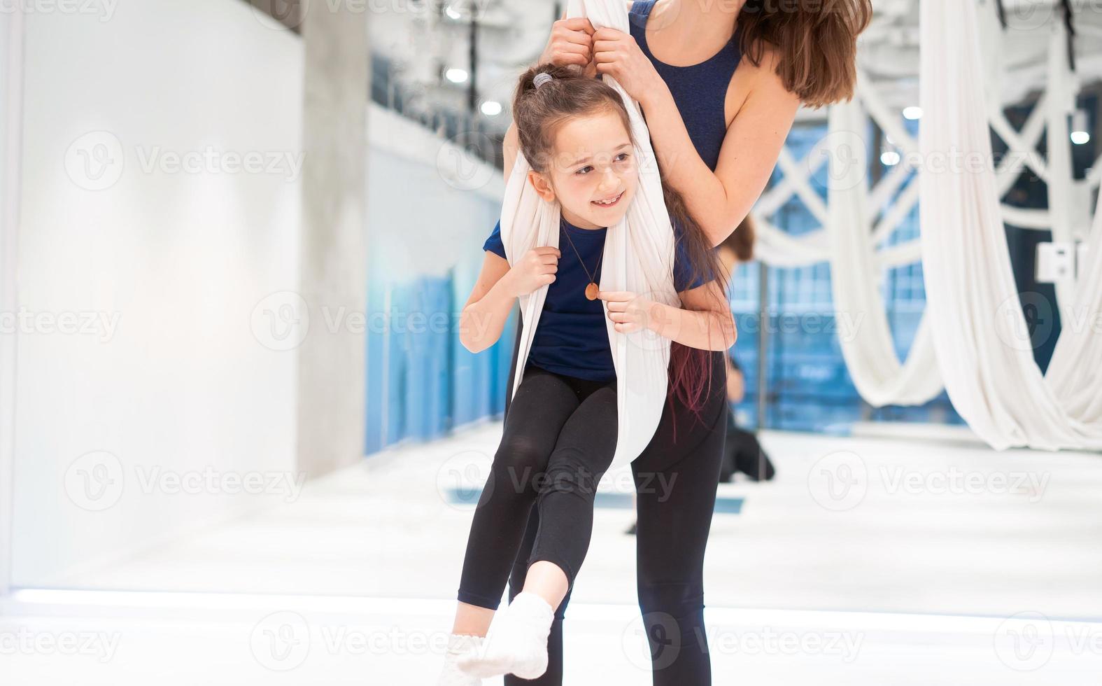 Mom and Daughter are doing yoga. Family in a gym. photo