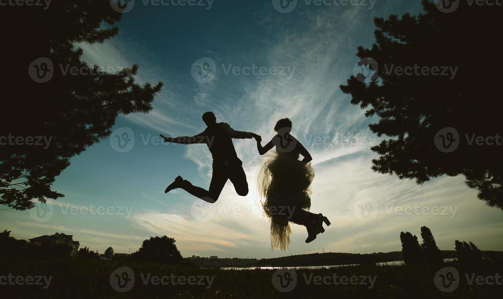 groom and bride jumping against the beautiful sky photo