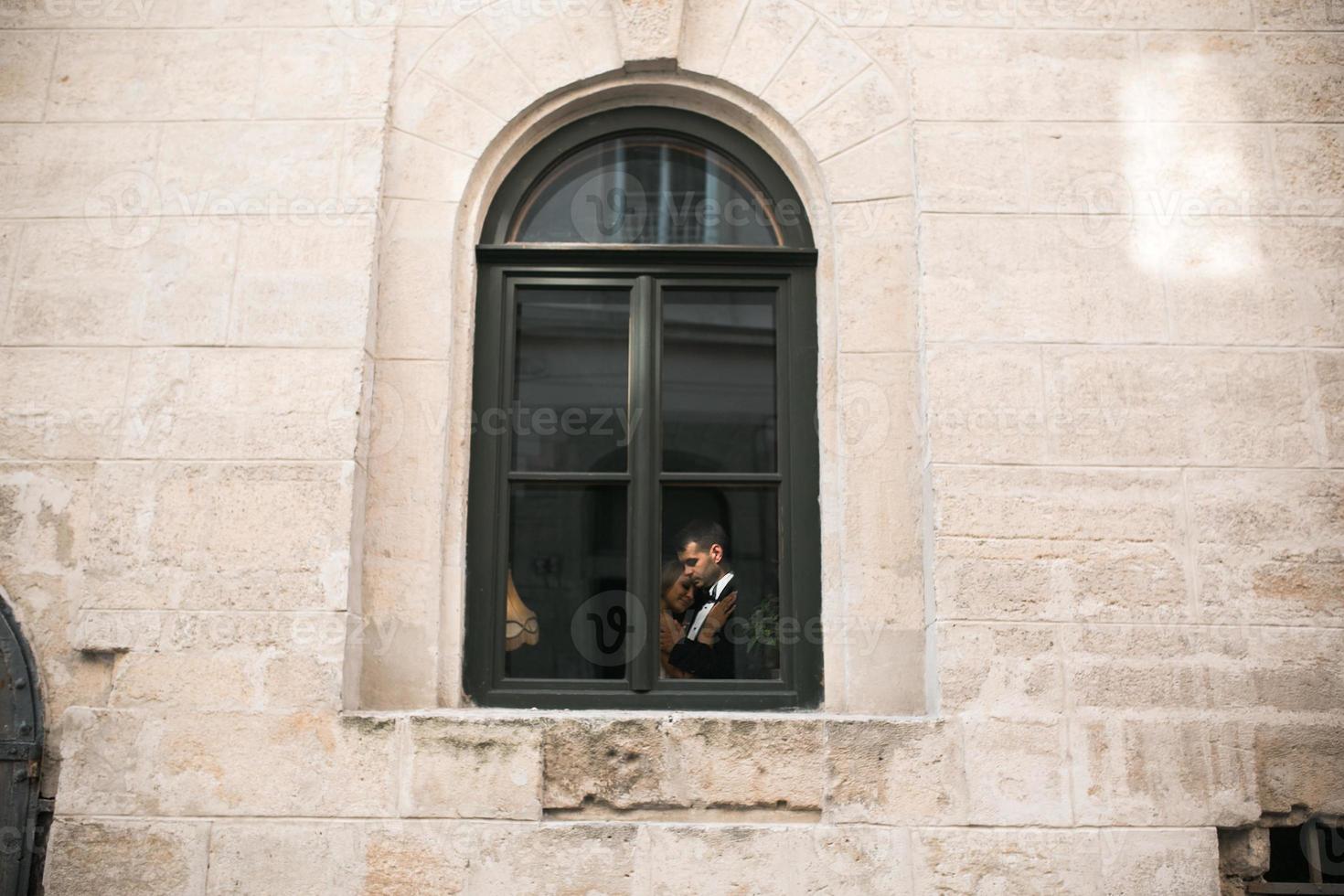 Wedding couple kissing in the window photo