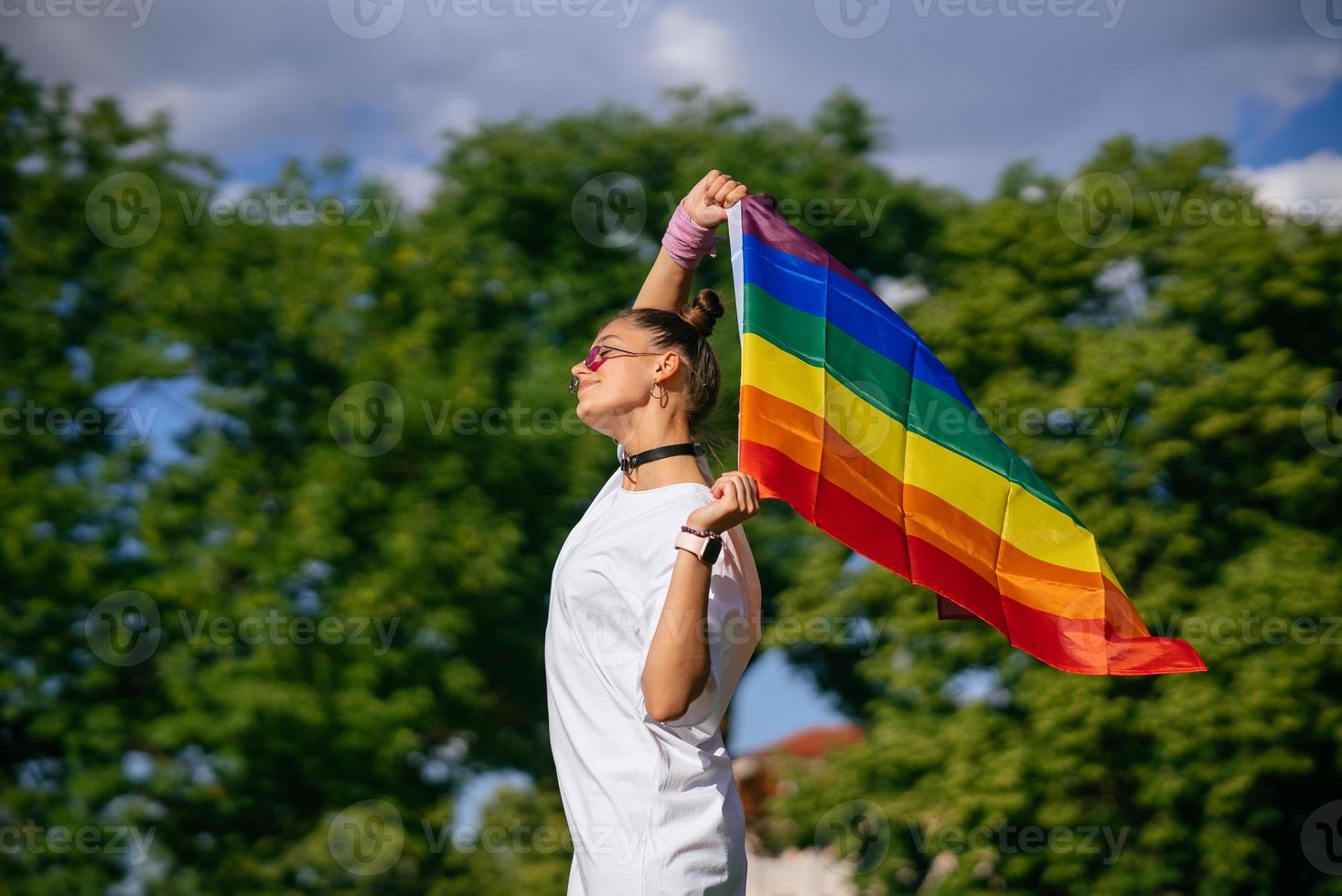 Young woman waving LGBT pride flag in the park. photo