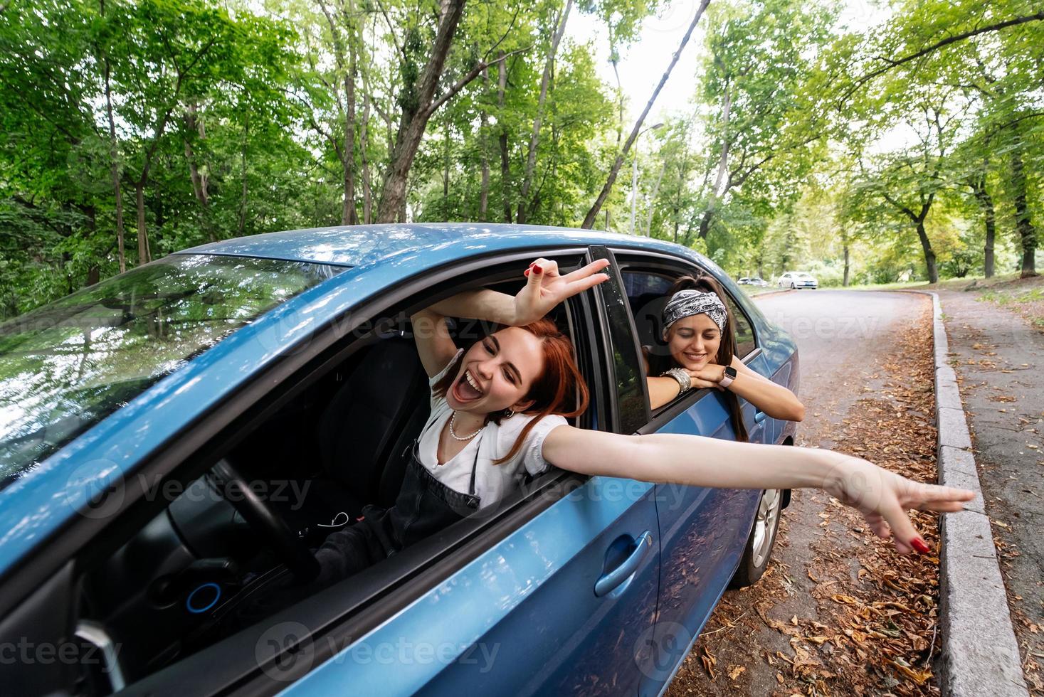 Two girlfriends fool around and laughing together in a car photo