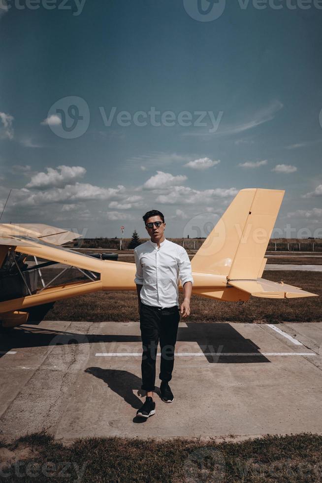 A man standing on the background of a small single engine plane. photo