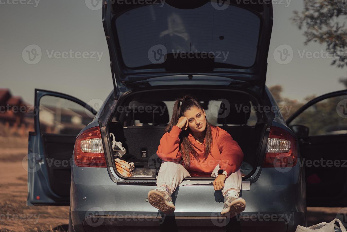 Attractive young woman resting in the trunk of a car photo