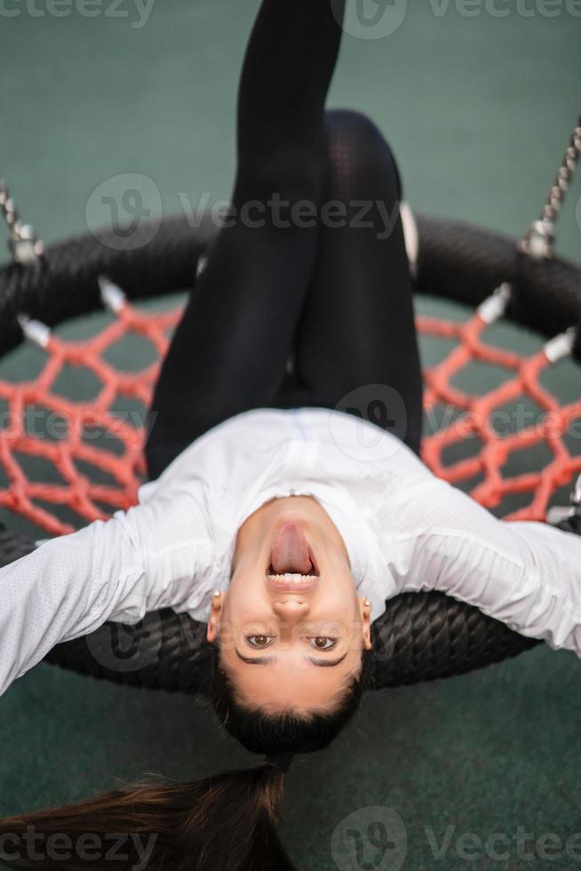 Young woman rides on a swing at the playground. photo