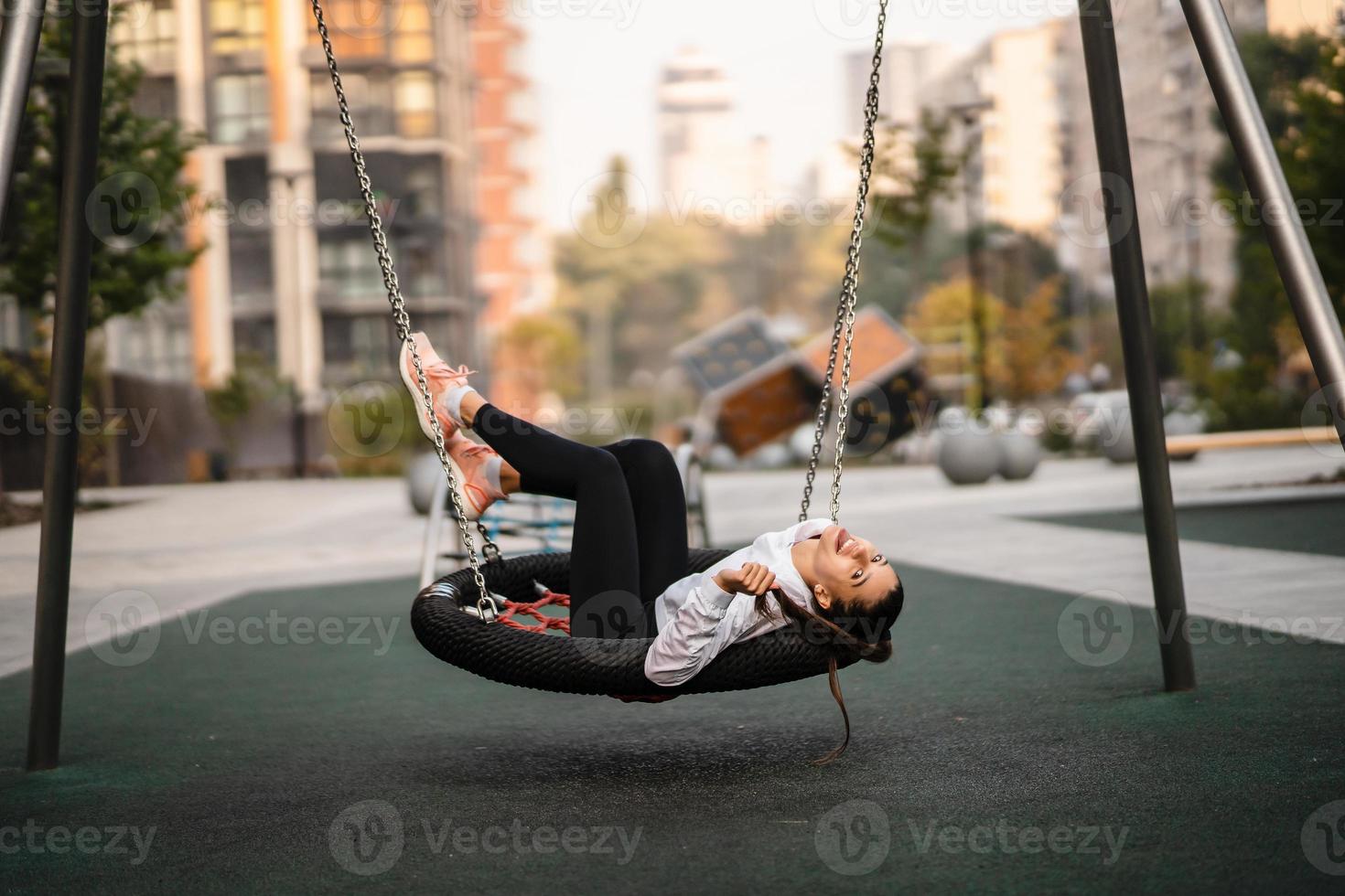 Young woman rides on a swing at the playground. photo