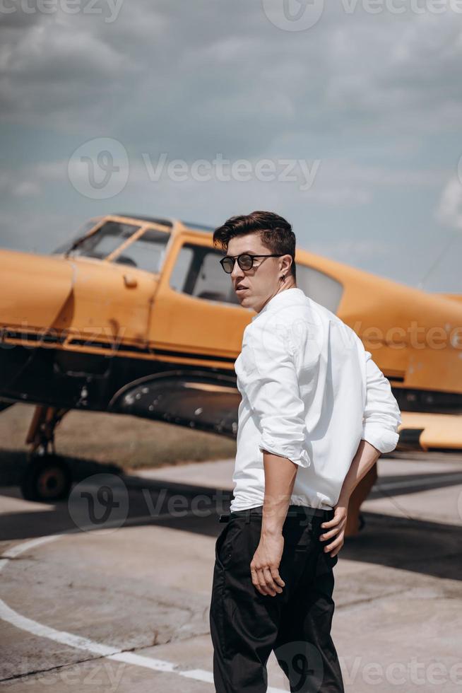 A man standing on the background of a small single engine plane. photo