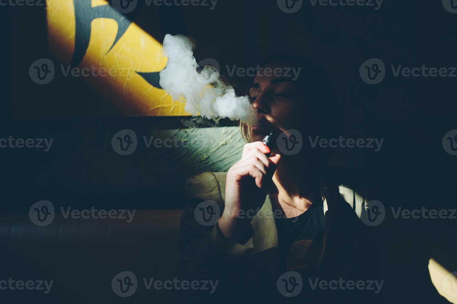 girl sits and smokes electronic cigarette photo