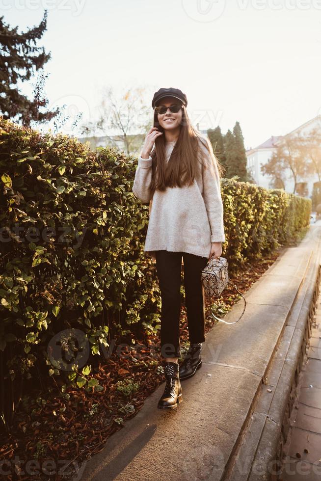 Beautiful young woman posing in the park near the hedge photo