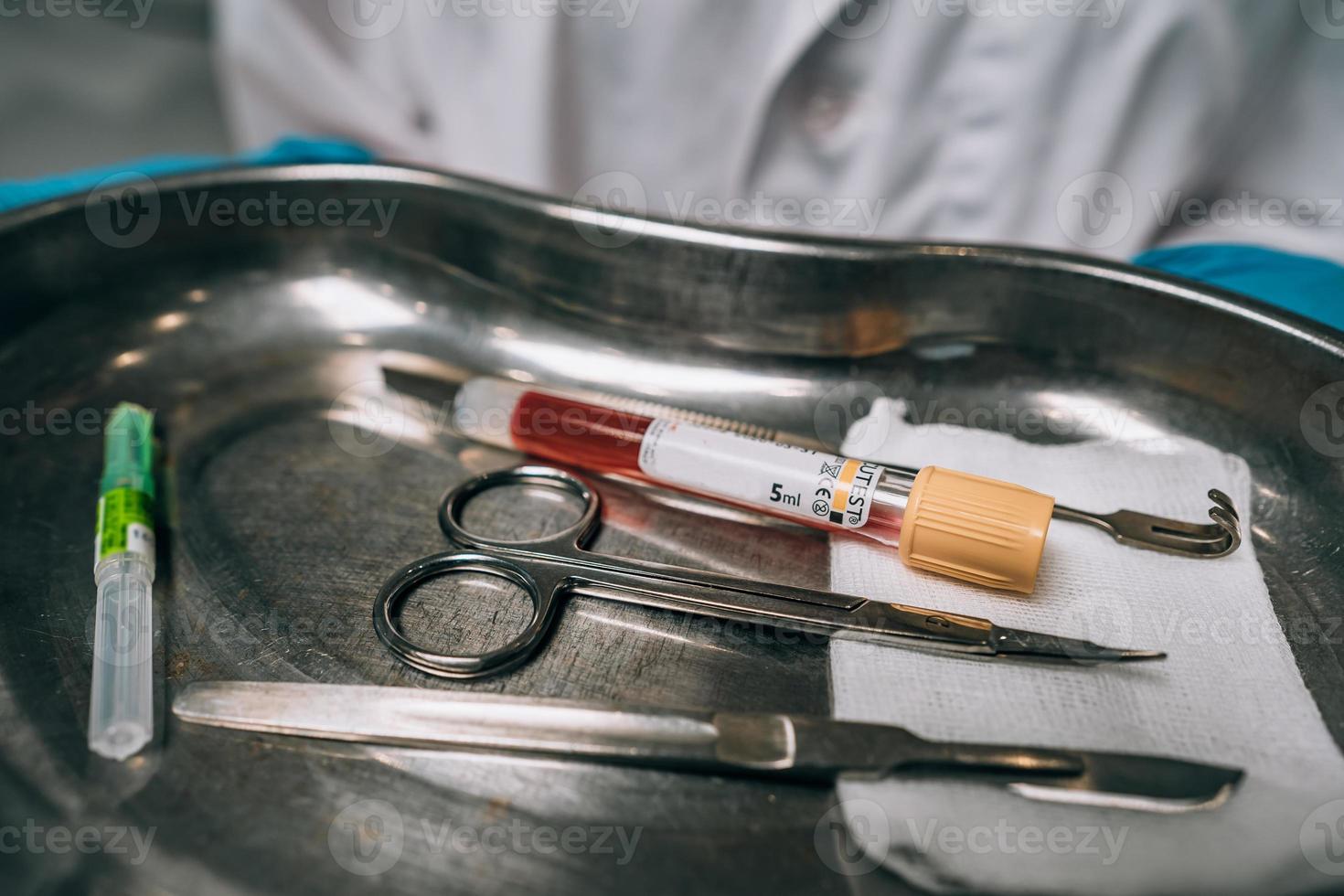 Nurse in rubber gloves holding a tray of surgical medical equipment photo