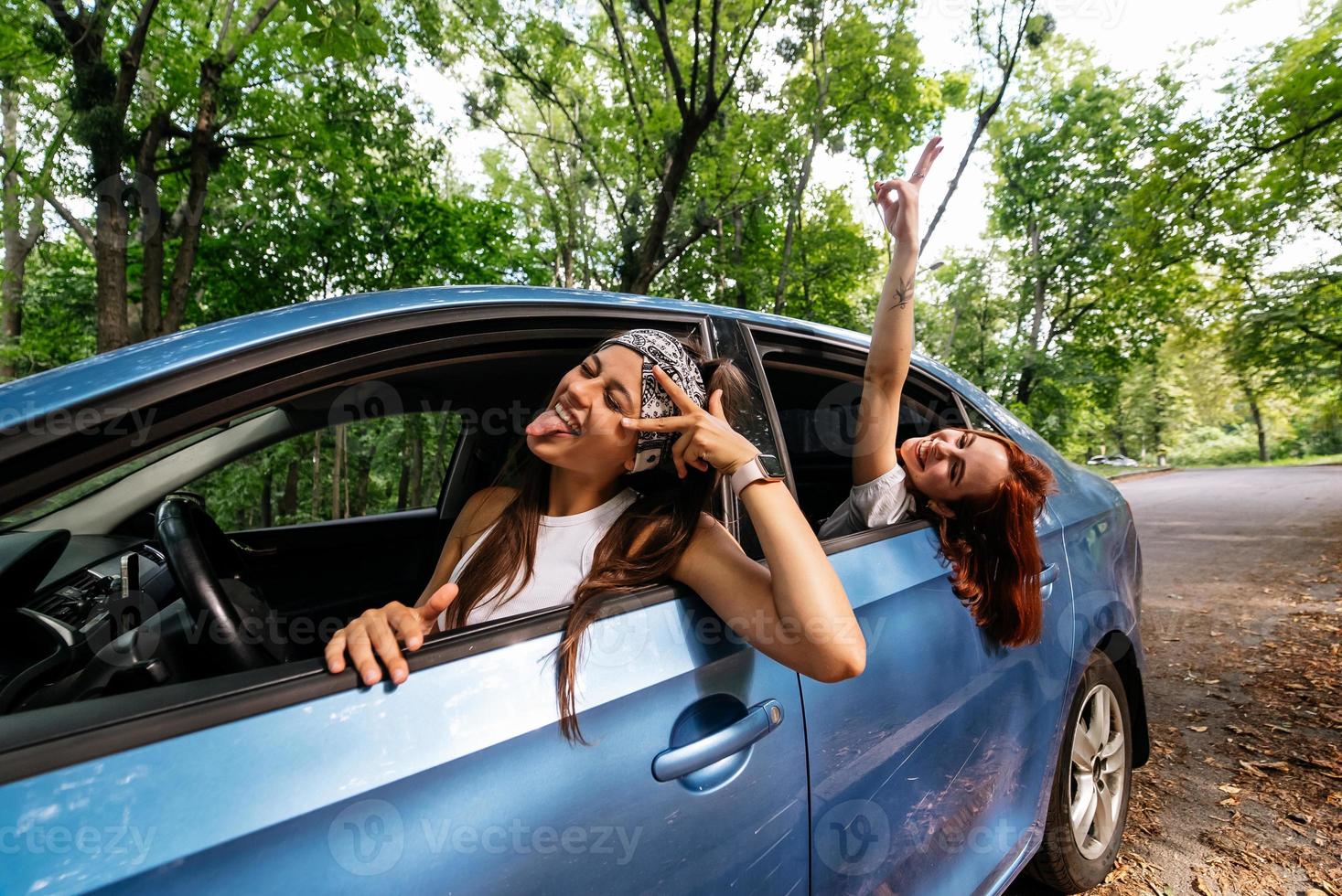 Two girlfriends fool around and laughing together in a car photo