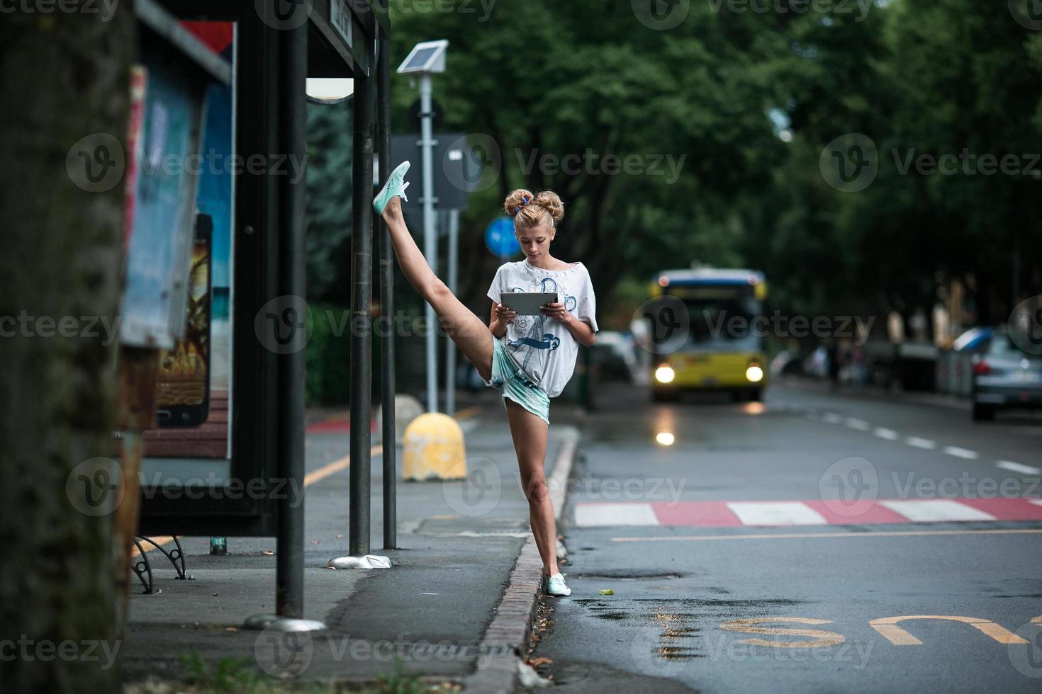 Cute girls with tablet on a bus station with a leg split photo