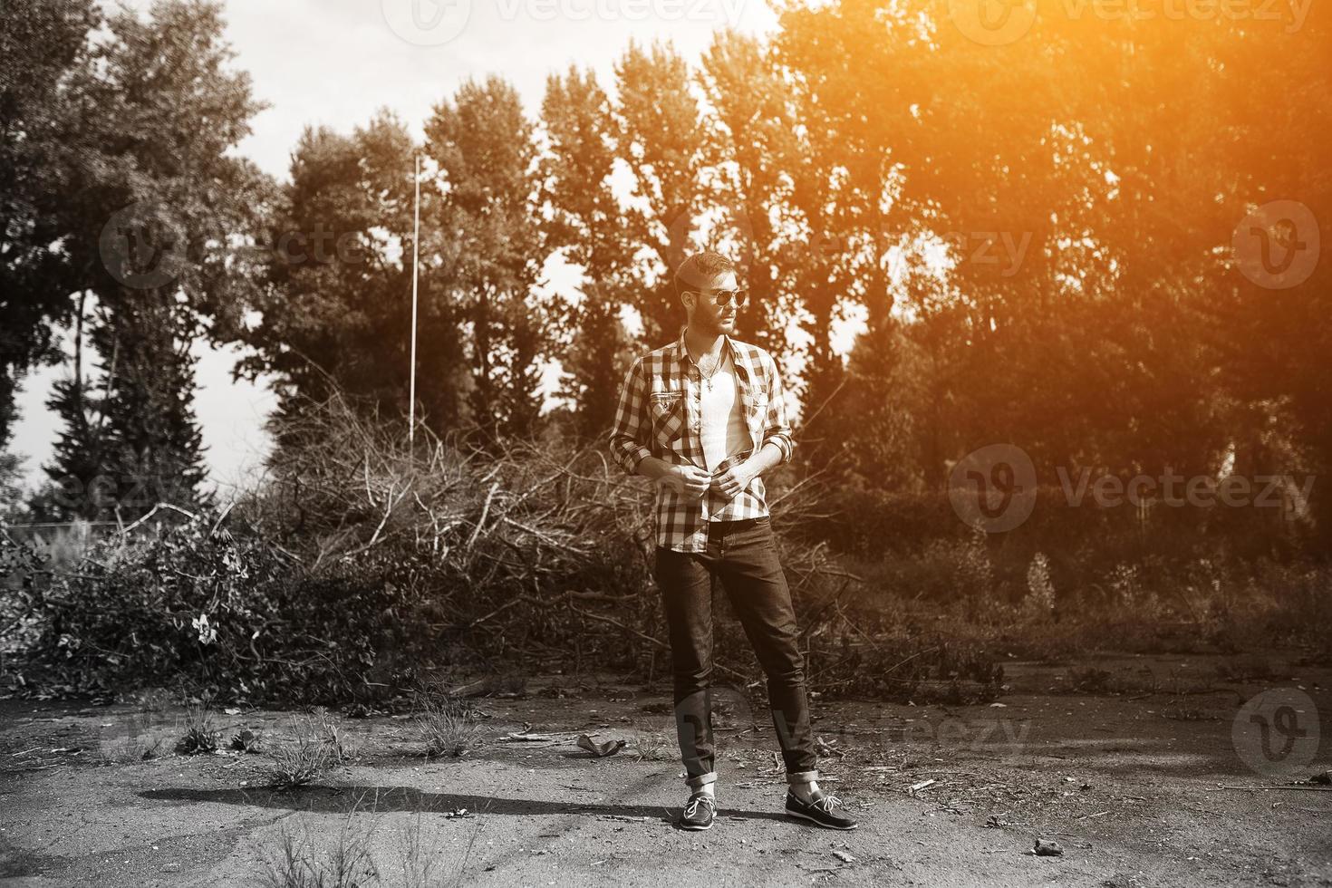 The man in the authentic boots and selvedge jeans  on a the background of branches photo