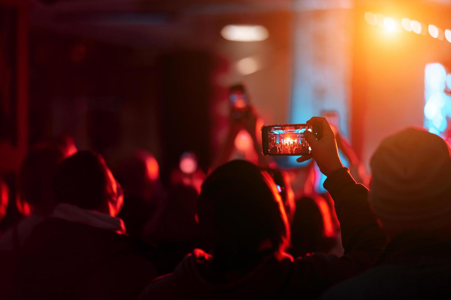 Person close up of recording video with smartphone during a concert. photo