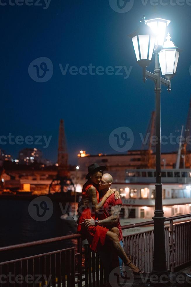 chico y chica abrazándose en un fondo del puerto nocturno foto