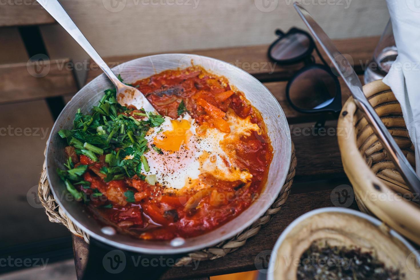 Shakshuka, Fried Eggs in Tomato Sauce on the Table photo