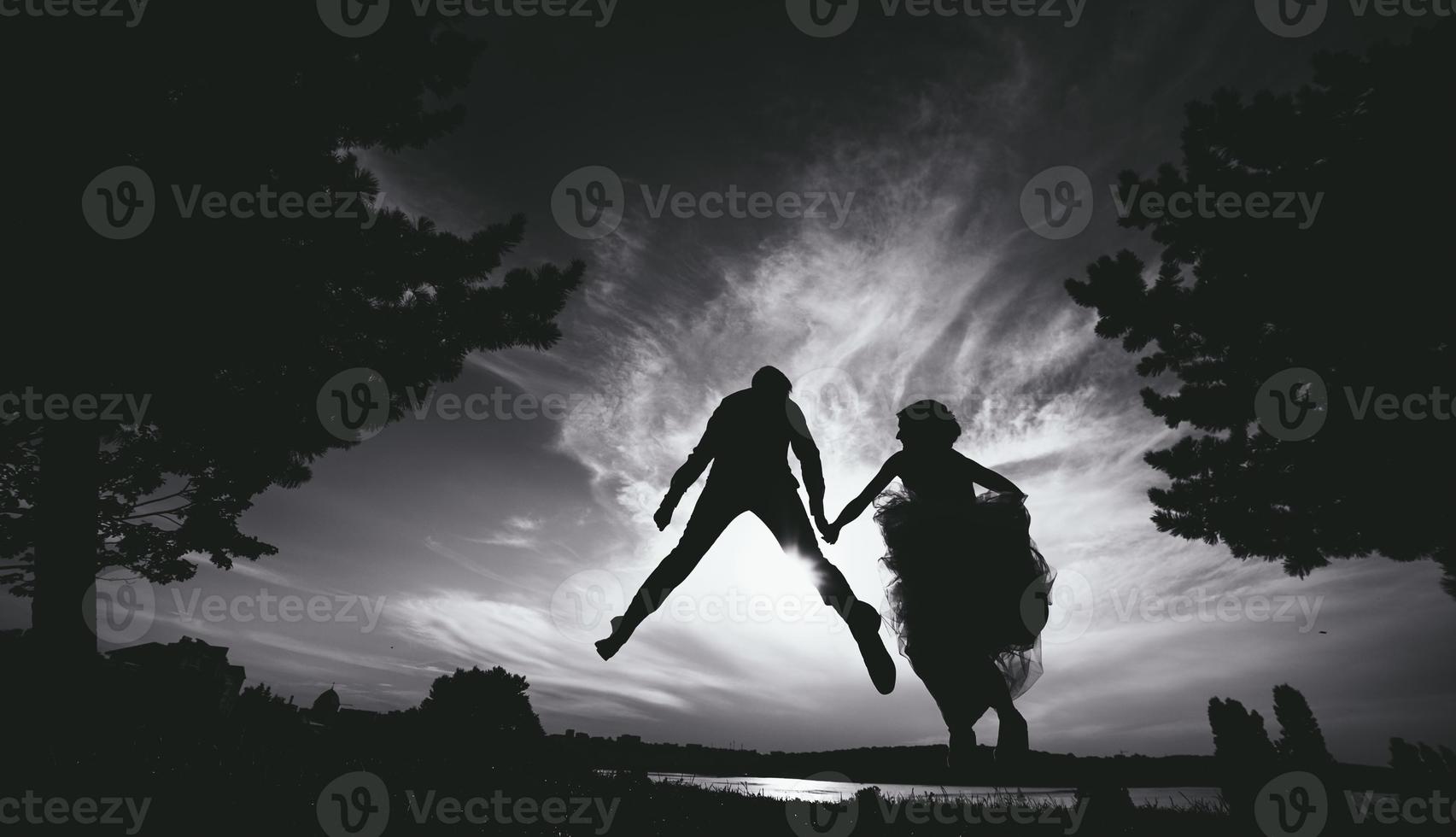 groom and bride jumping against the beautiful sky photo