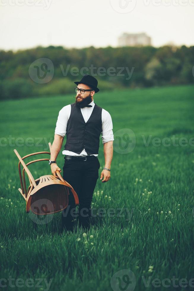 Bearded man carries a chair on the field photo